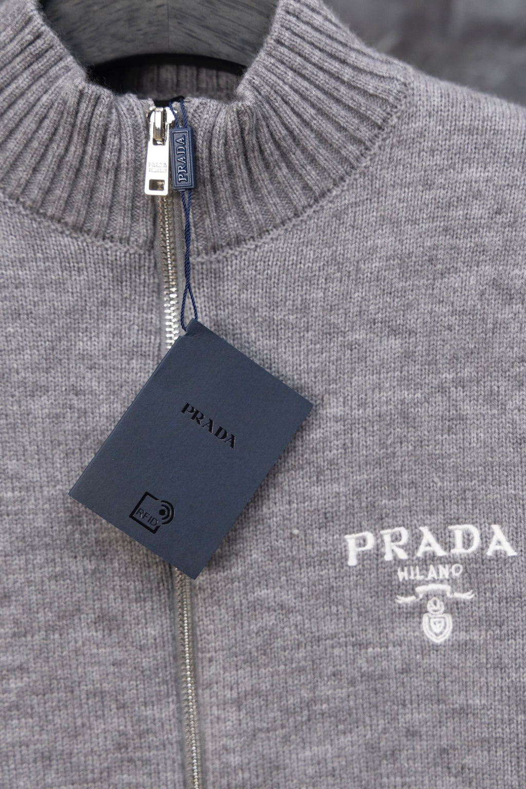 Gray Prada knit zip sweater close-up of ribbed stand collar, PRADA logo and tag