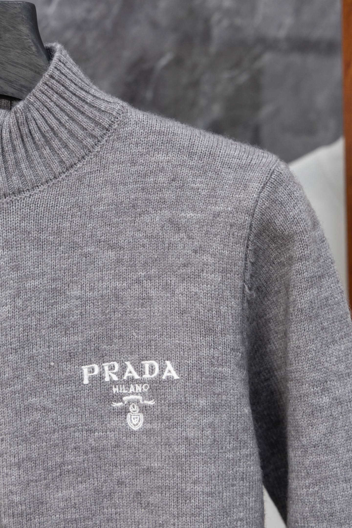 Gray Prada knit sweater shoulder and chest close-up with PRADA MILANO logo