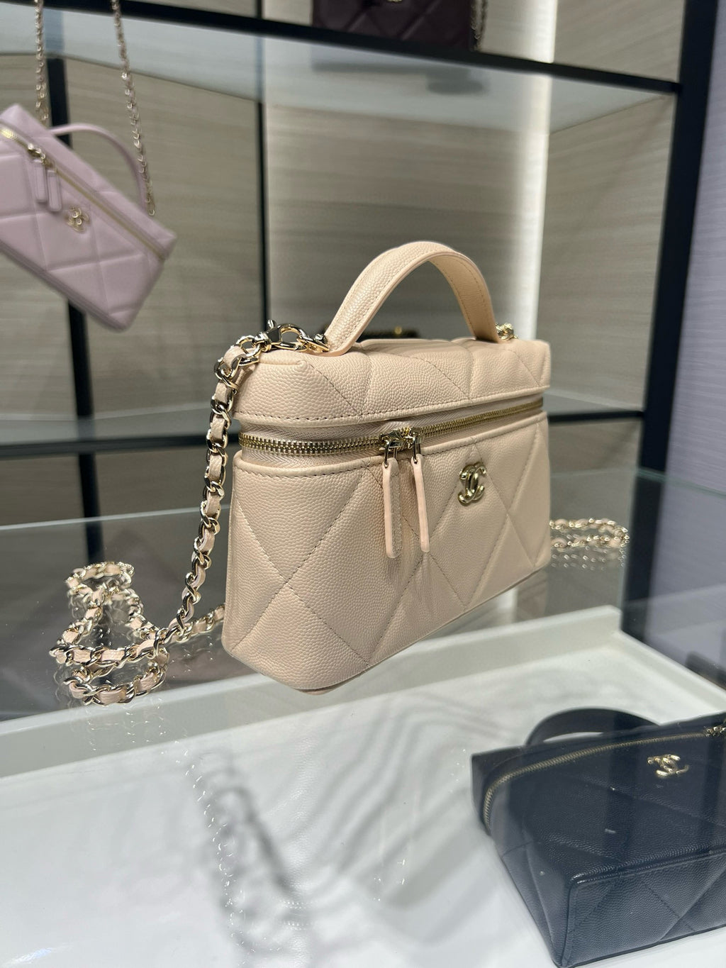 Cream mini top-handle handbag with quilted finish, zipper pocket, and gold chain