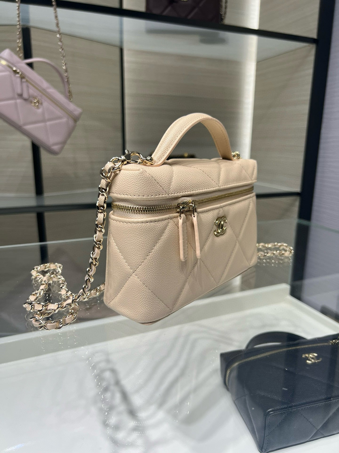 Cream mini top-handle handbag with quilted finish, zipper pocket, and gold chain
