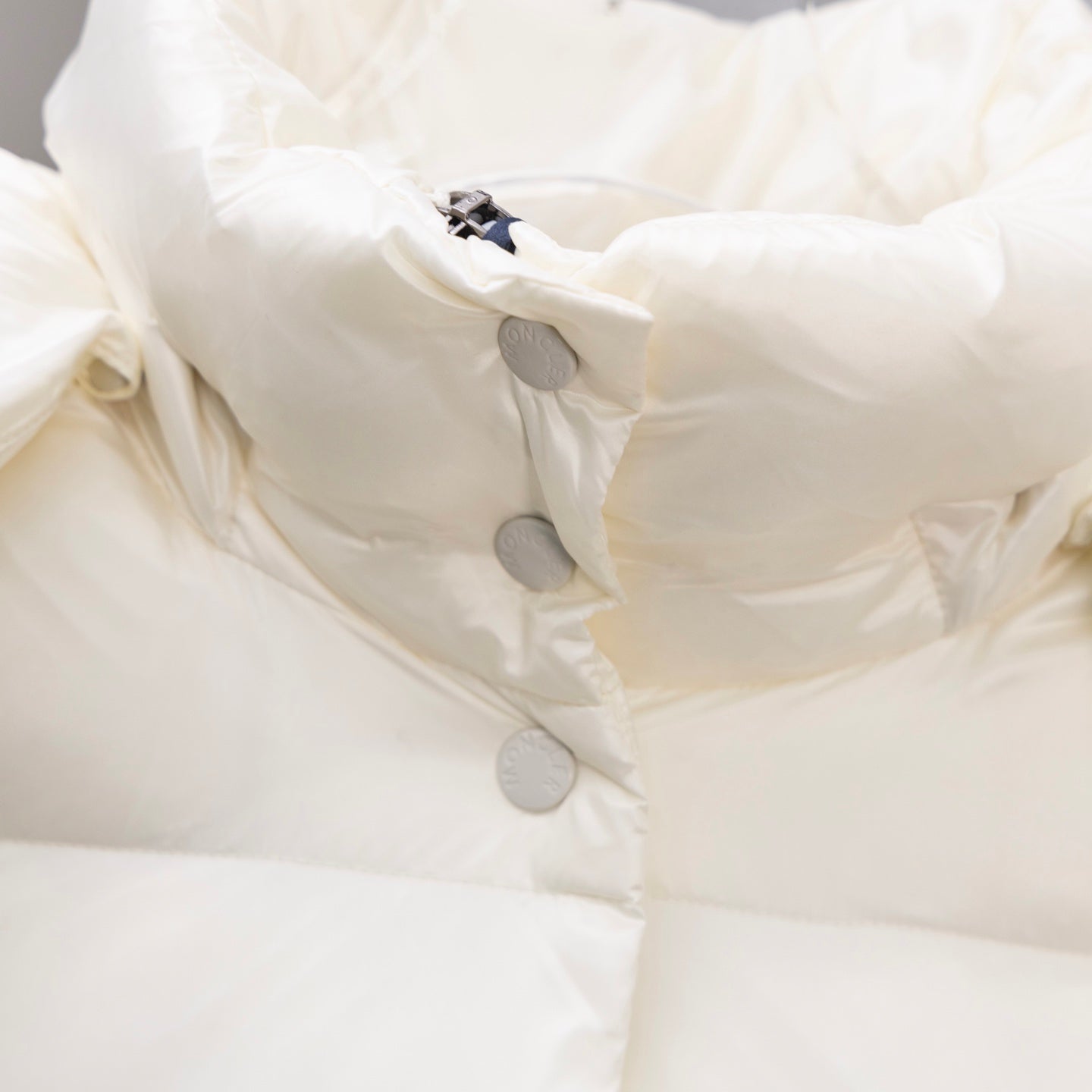 White puffer jacket close-up of front snap buttons and quilted padding