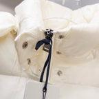 White puffer jacket close-up of metal snaps and navy drawstring tie