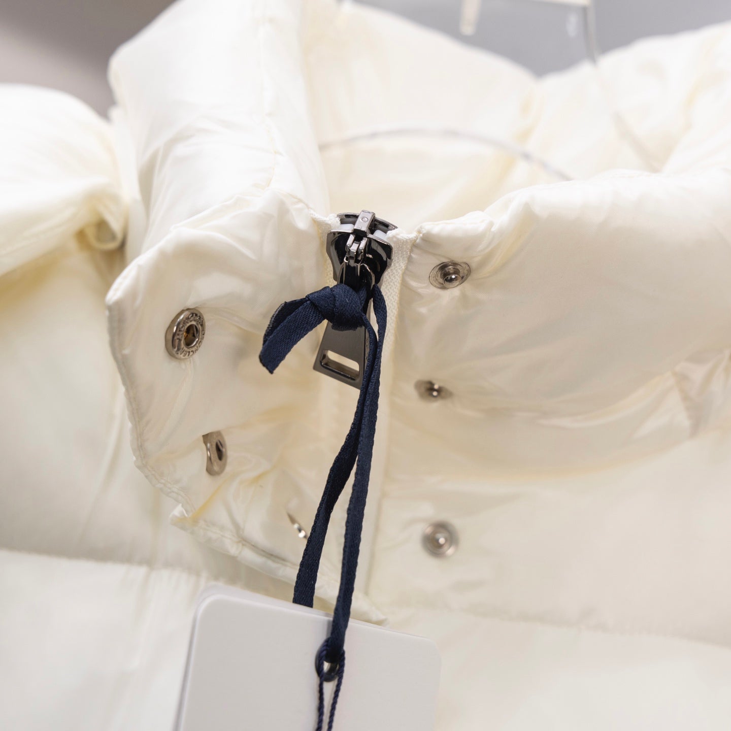 White puffer jacket close-up of metal snaps and navy drawstring tie