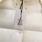 White puffer jacket close-up with brand tag hanging from inner snap placket