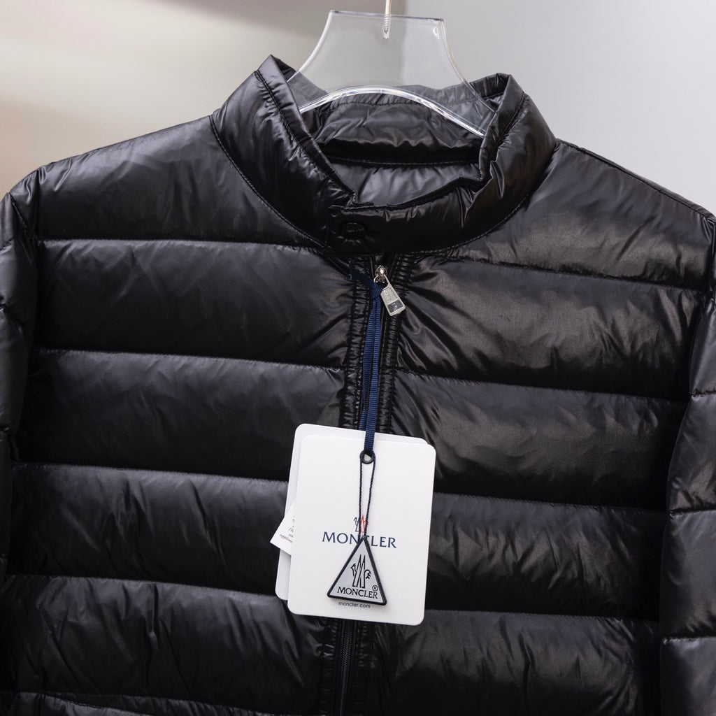 Black puffer jacket close-up: high collar, front zip, quilted shell with hang tags