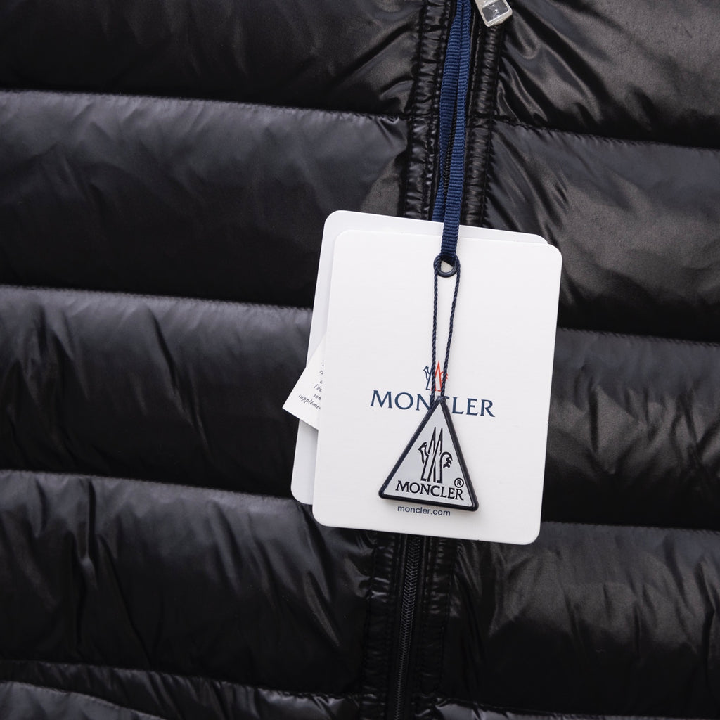 Black puffer jacket with hanging Moncler tag on blue zipper pull