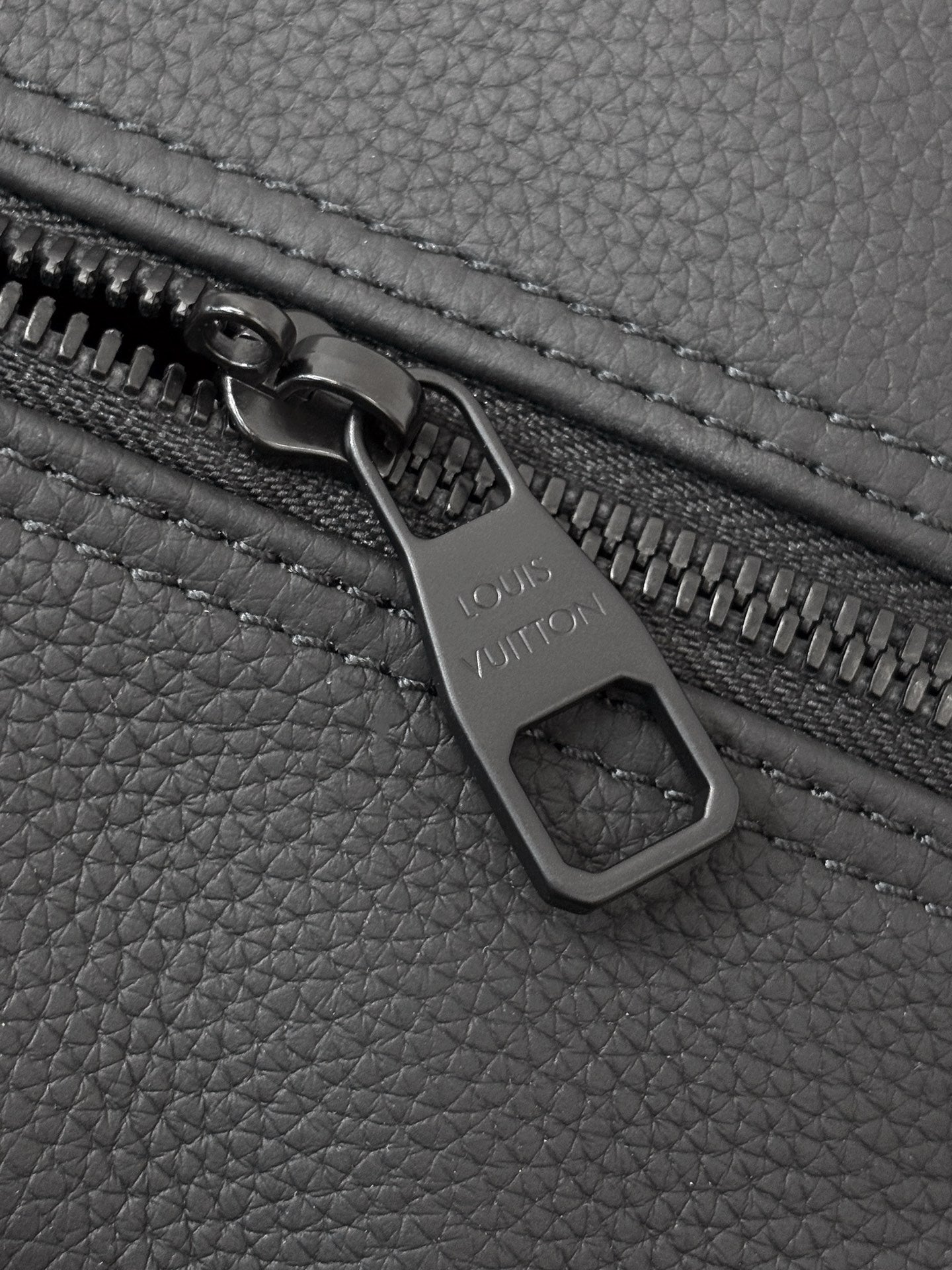 Dark gray leather zipper pull with engraved logo and zipper track