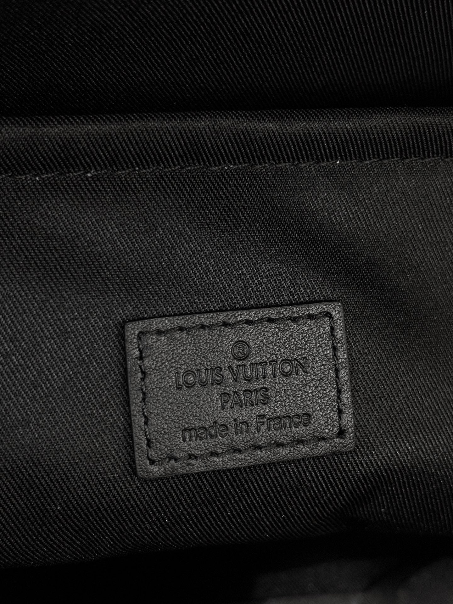 Louis Vuitton bag detail: embossed logo patch on dark fabric