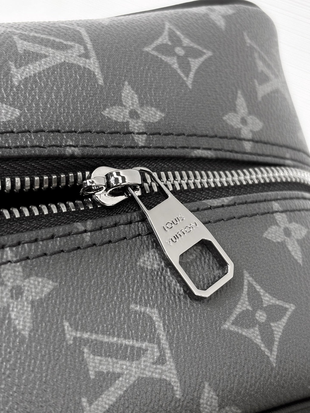Louis Vuitton bag close-up of dark monogram canvas zipper with engraved pull tab