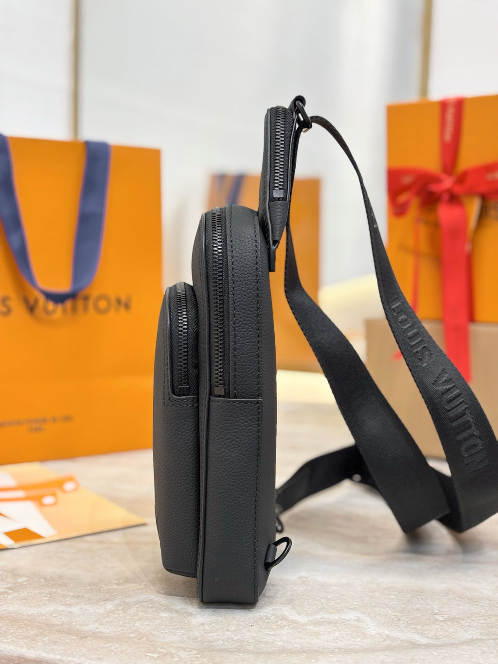 Black leather crossbody bag with front zipper and adjustable shoulder strap.