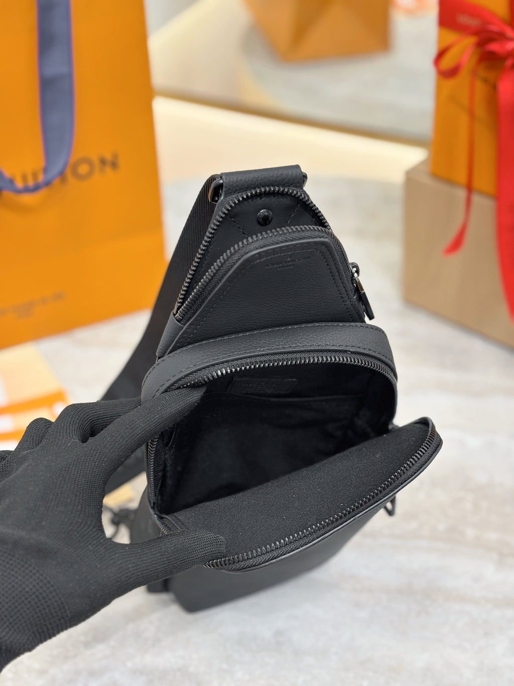 Black leather crossbody bag with open top zipper and fabric lining.