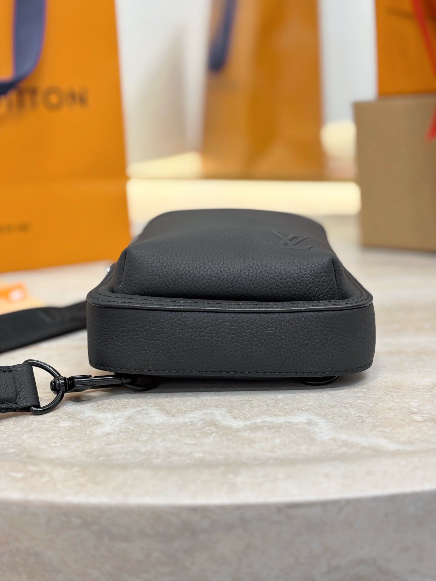 Black leather crossbody bag with zip top and flat strap loop.