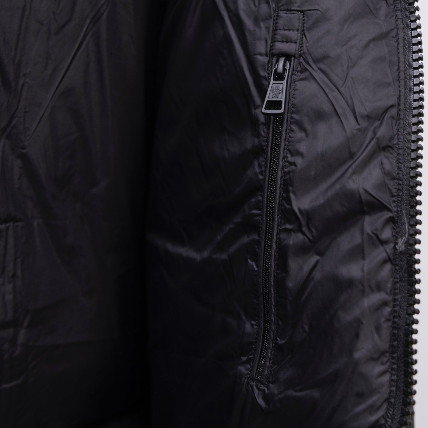 Dark puffer jacket sleeve close-up with zipper and pull tab