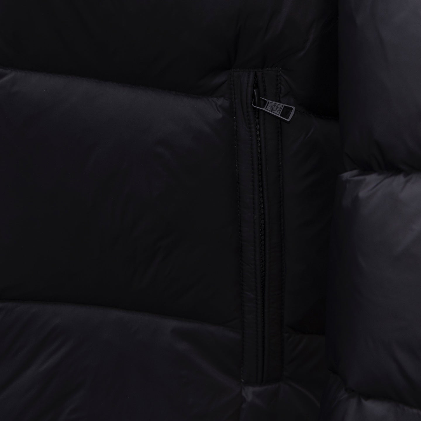 Dark puffer jacket side close-up of center front zipper