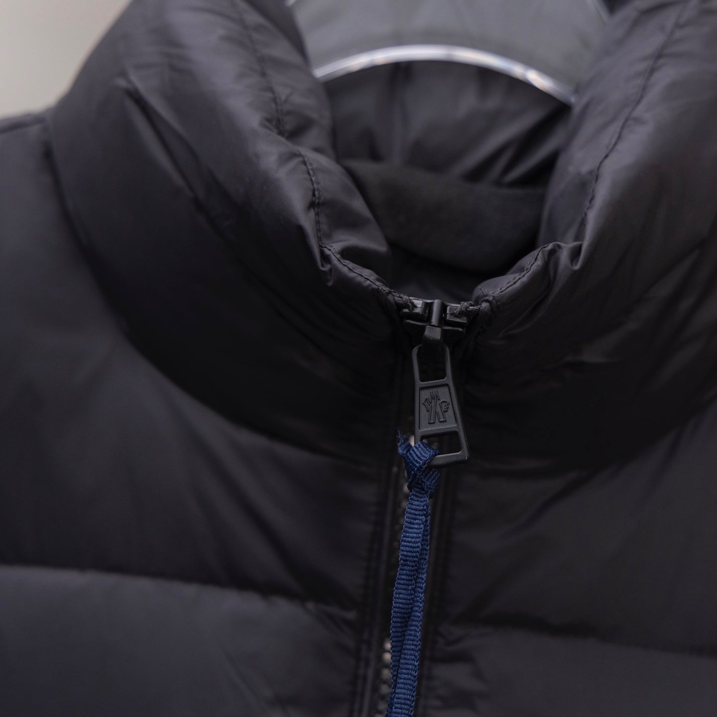 Dark puffer jacket close-up of zip pull with branding tag