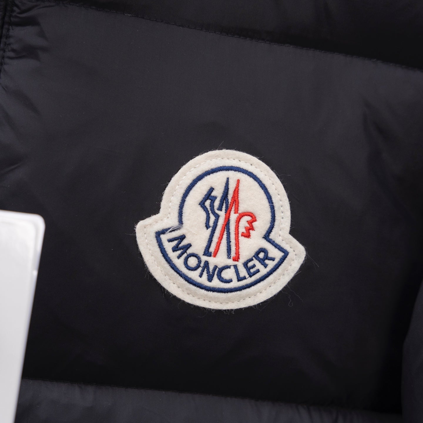 Dark puffer jacket interior with circular embroidered brand logo patch