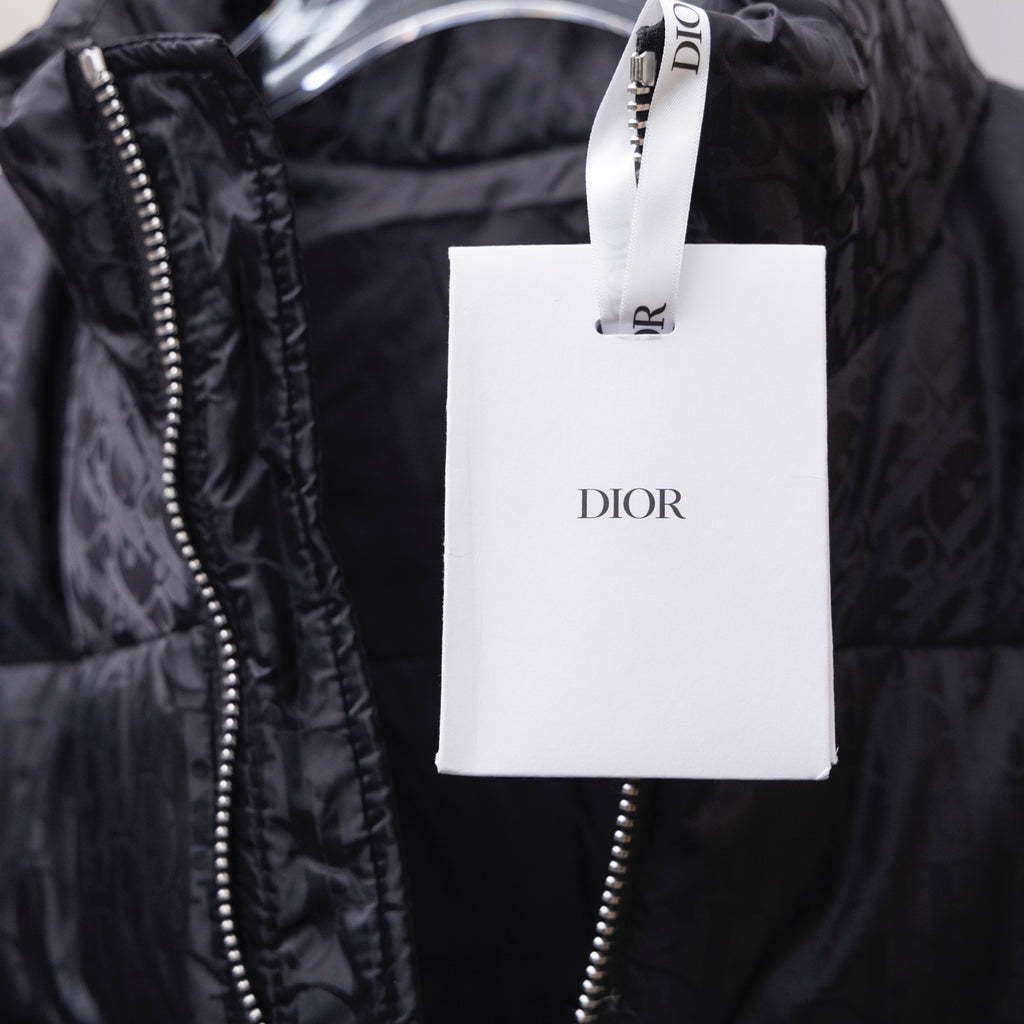 Black Dior puffer jacket with zipper and hanging Dior retail tag.