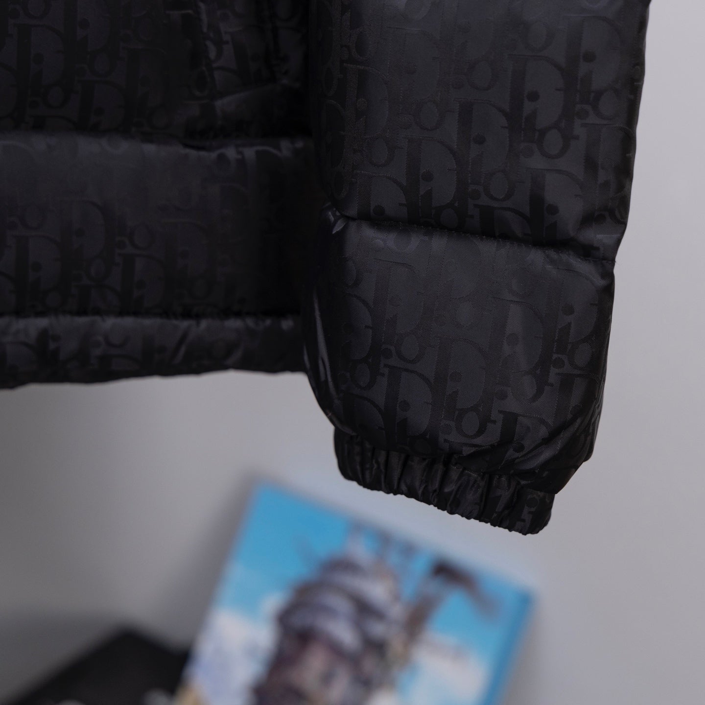 Black Dior puffer jacket sleeve cuff with quilted monogram pattern.