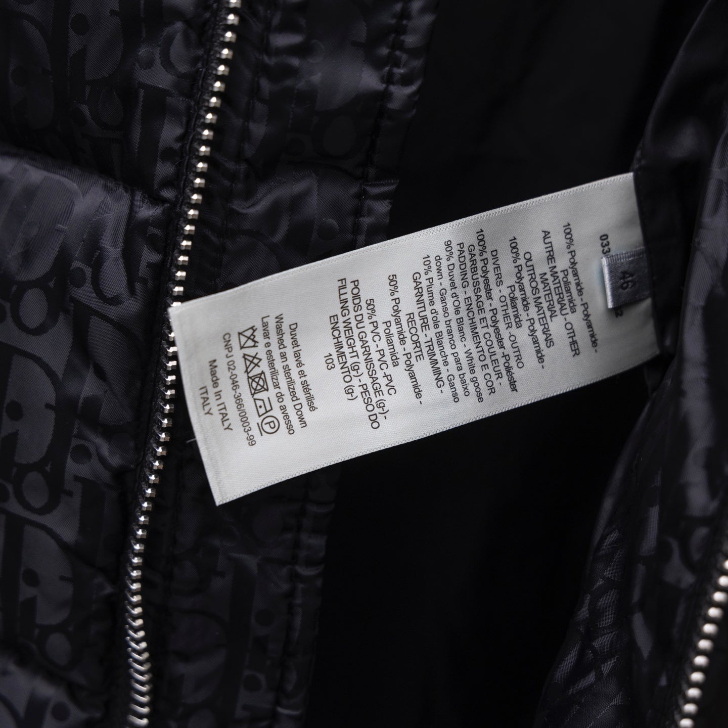 Black Dior puffer jacket care label tag near front zipper.