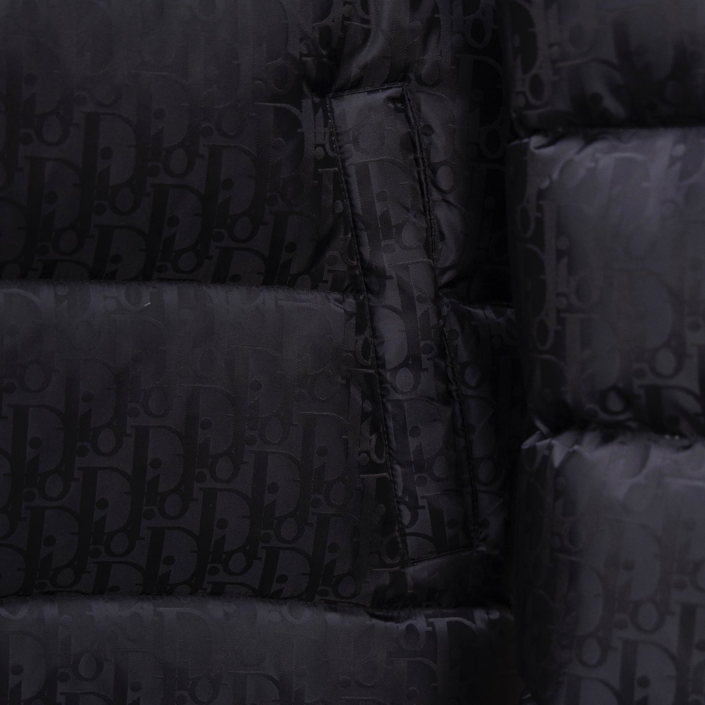 Black Dior puffer jacket front with zipper and monogram pattern close-up.
