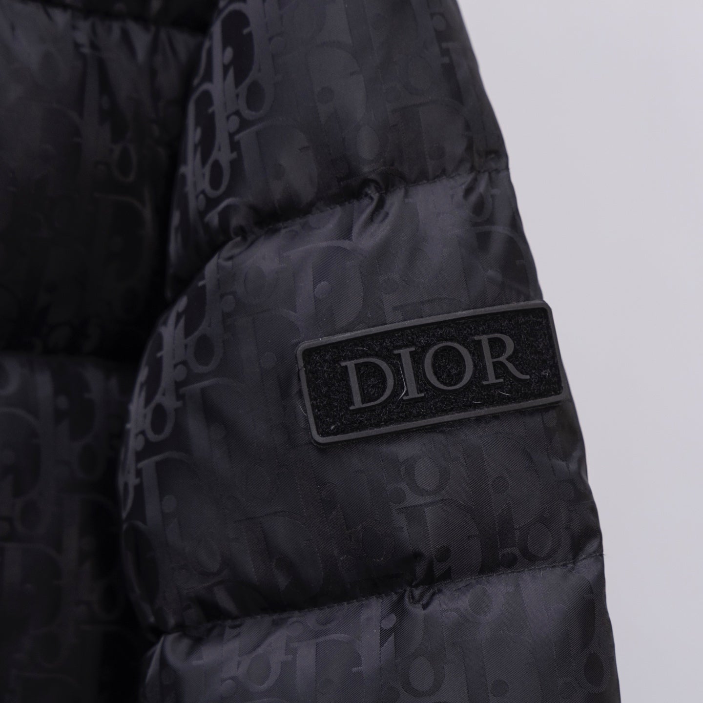 Black Dior puffer jacket chest patch with DIOR logo badge.