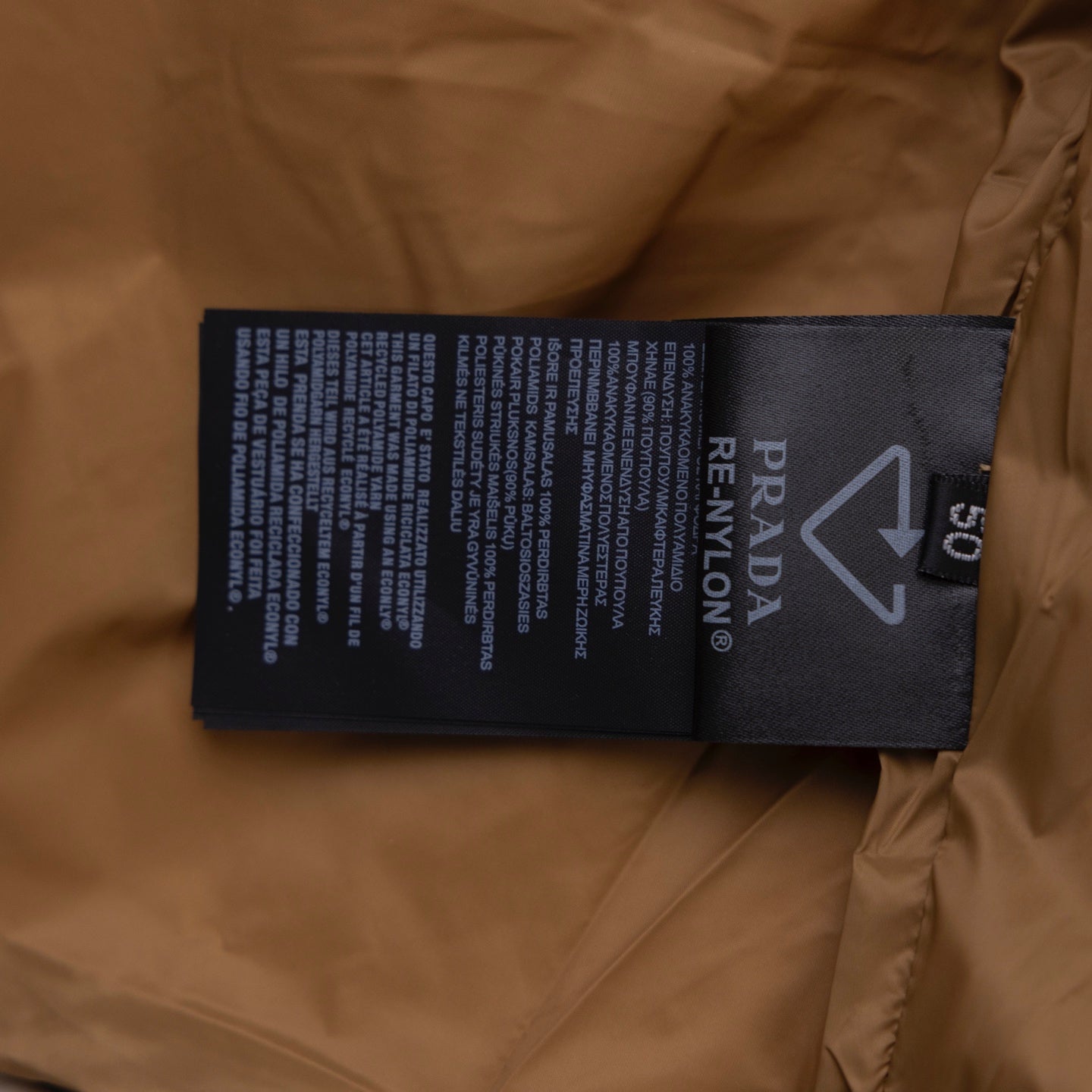 Prada care label and size tag inside puffer jacket on tan lining