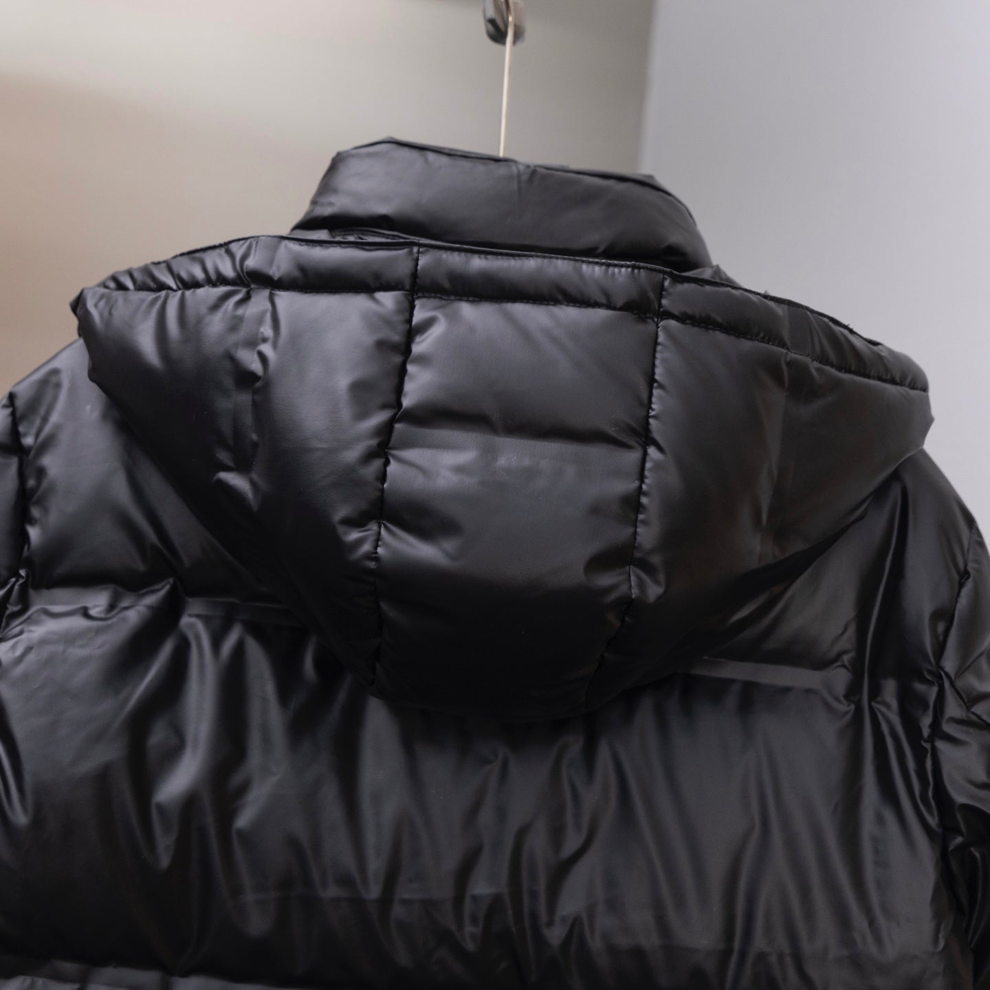 Long puffer jacket back view, dark hood and quilted channel stitching