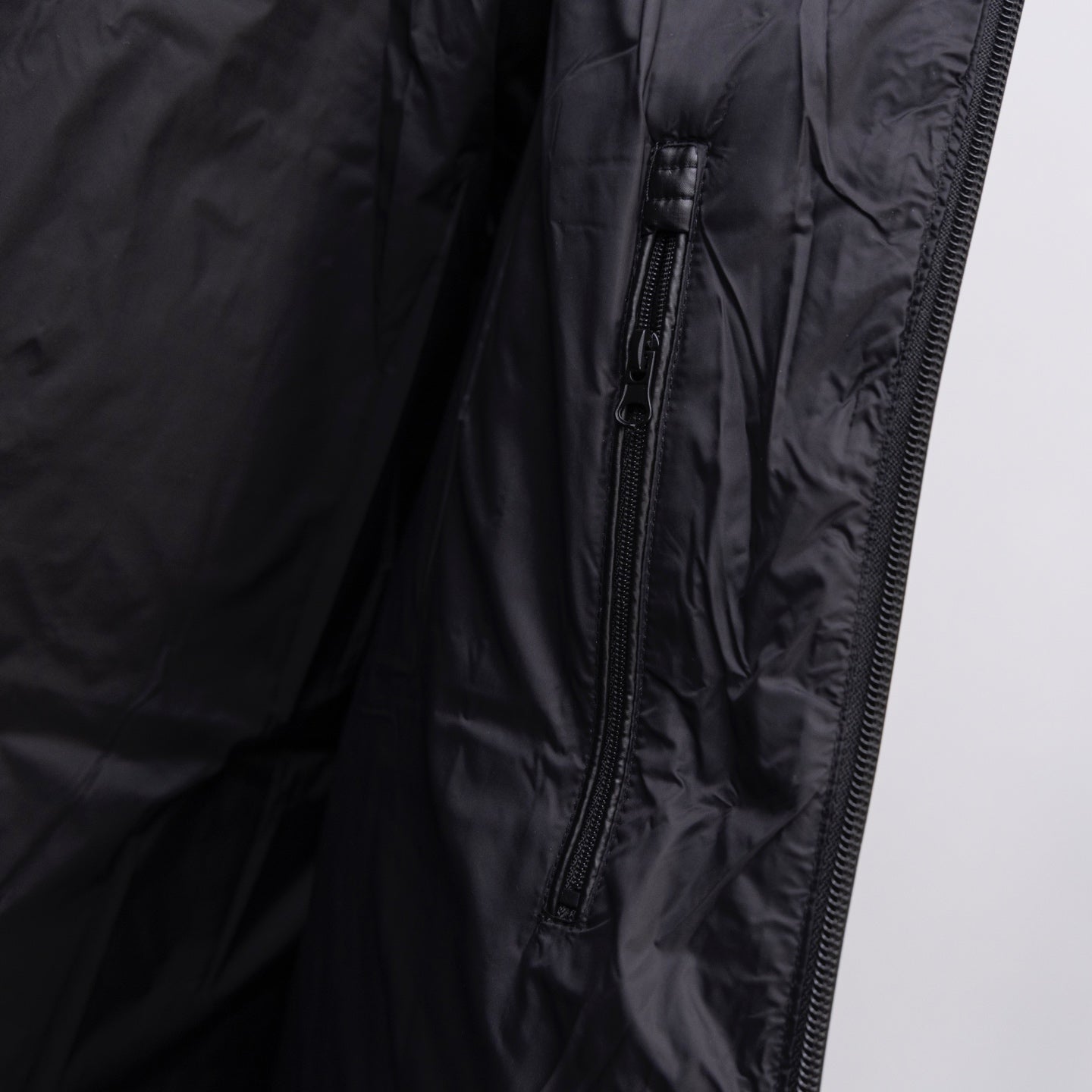 Long puffer jacket close-up of front side zipper on dark fabric