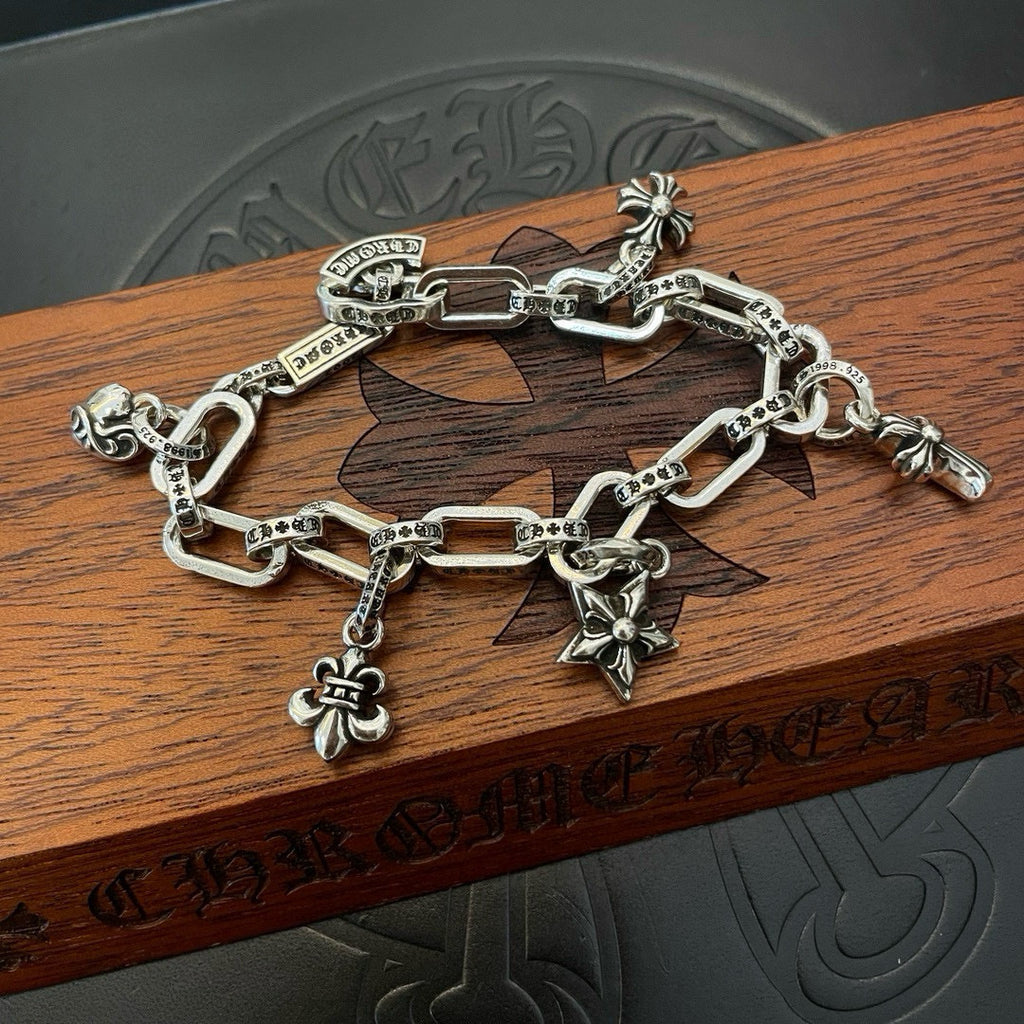 Silver tone charm bracelet on wooden lid with chain links and dangling star cross charm