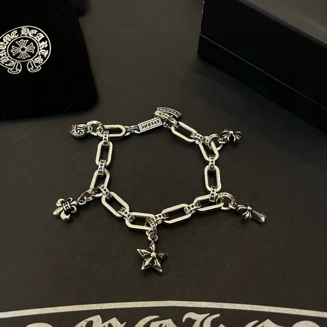Silver tone charm bracelet with linked chain and star cross and flower charms