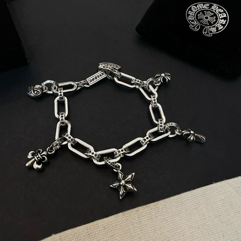 Silver tone charm bracelet with chain links and star cross, flower, and small ring charms