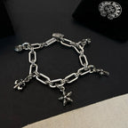 Silver tone charm bracelet with chain links and star cross, flower, and small ring charms