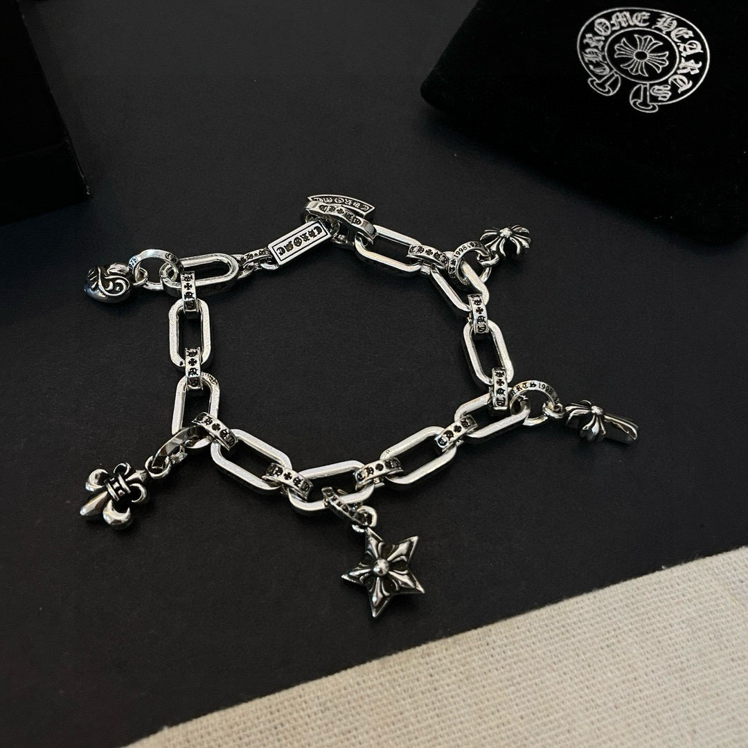 Silver tone charm bracelet with chain links and star cross, flower, and small ring charms