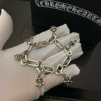 Silver tone charm bracelet close-up with chunky links and star and flower pendants