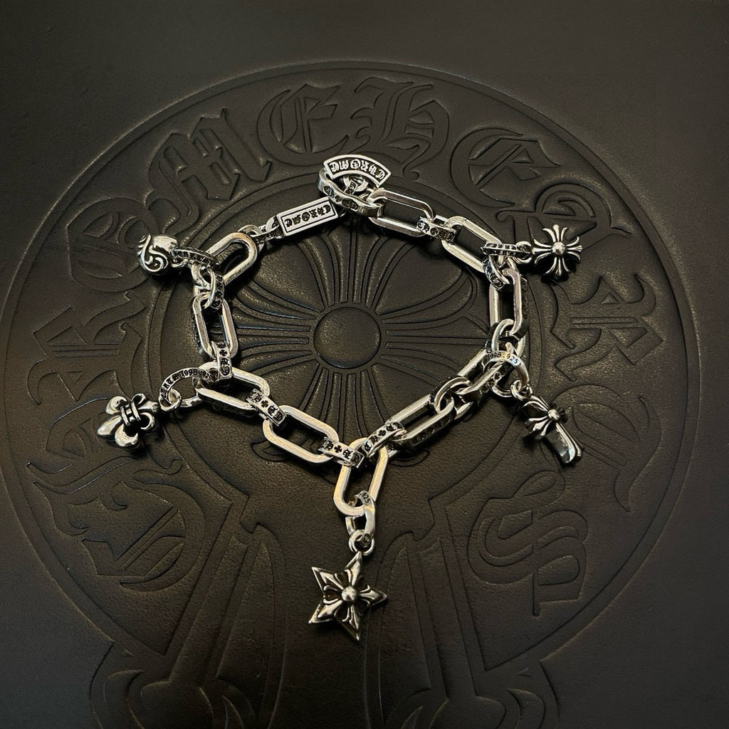 Silver tone charm bracelet resting on embossed surface with star cross and flower charms