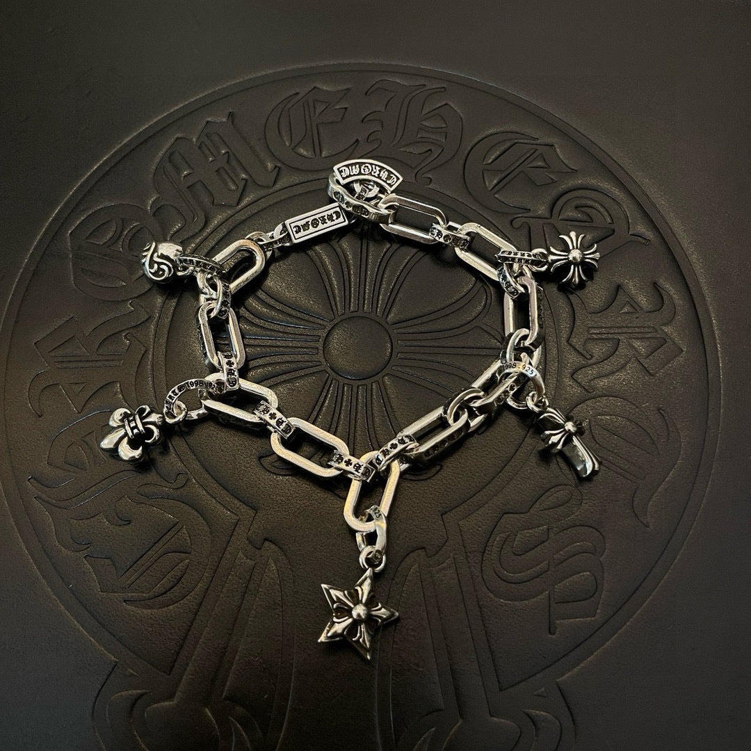 Silver tone charm bracelet resting on embossed surface with star cross and flower charms