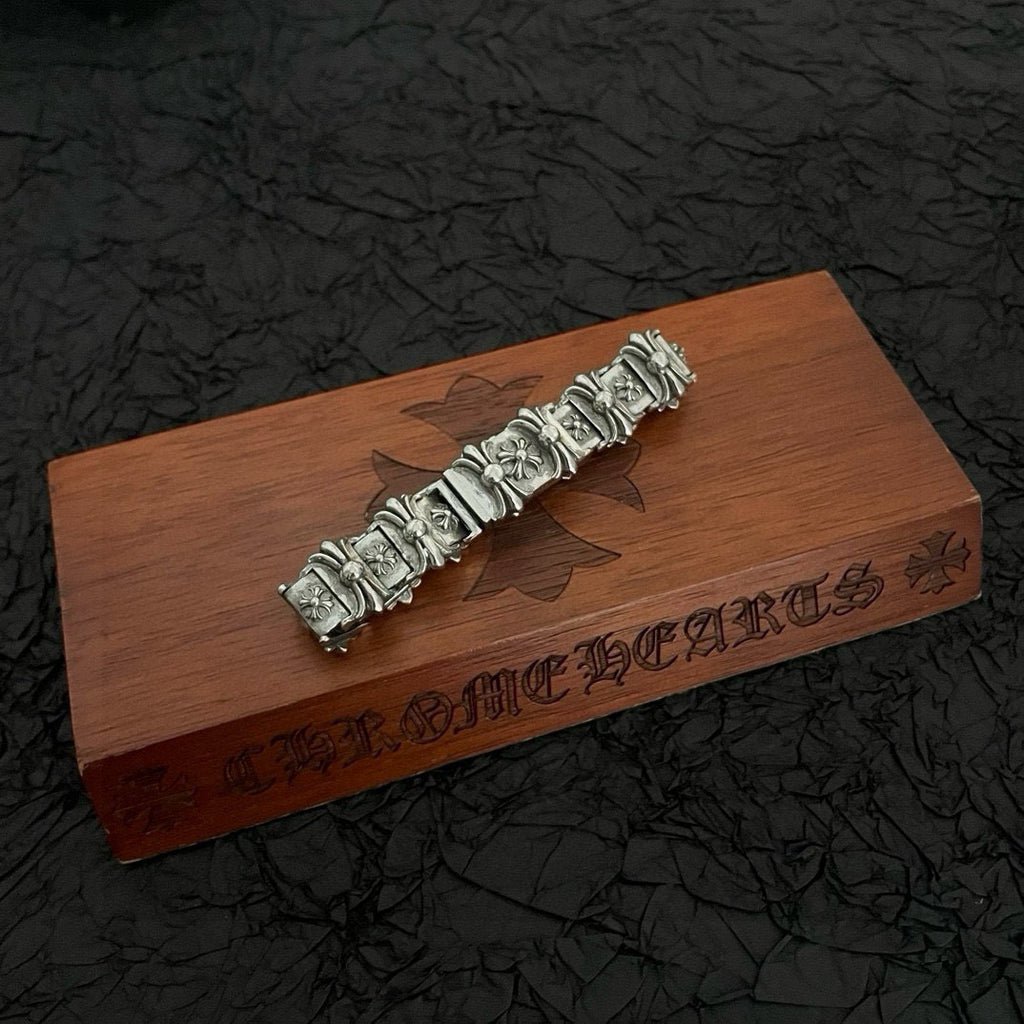 Silver-tone bracelet with repeating engraved rectangular link panels and floral accents