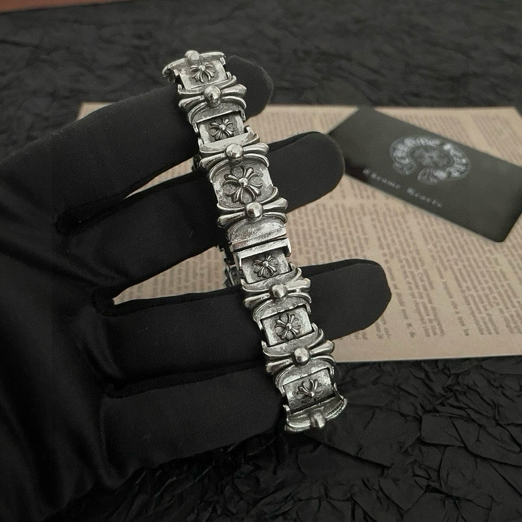 Silver-tone charm bracelet with raised floral links and rectangular panel segments