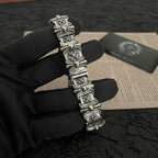 Silver-tone charm bracelet with raised floral links and rectangular panel segments
