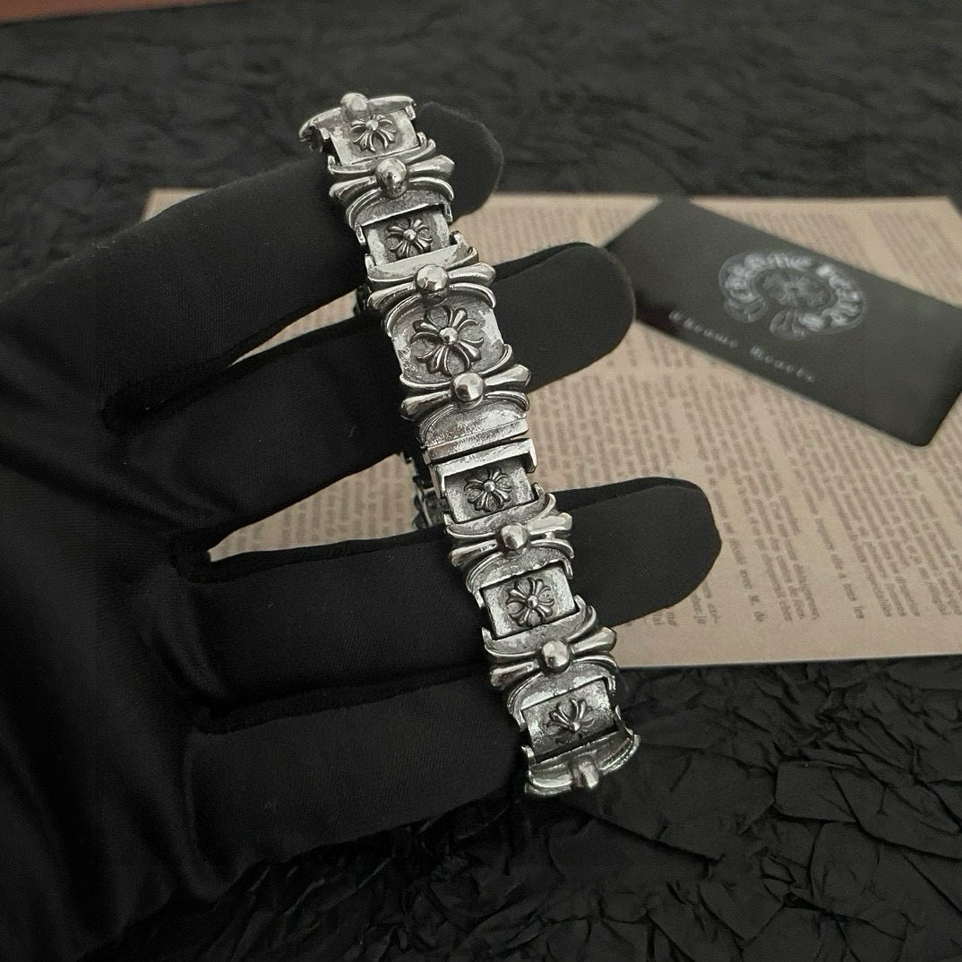 Silver-tone charm bracelet with raised floral links and rectangular panel segments