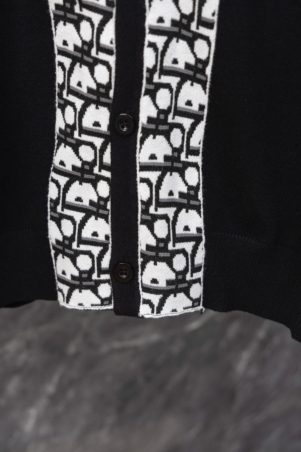 Black cardigan front hem with white patterned trim and two button closures