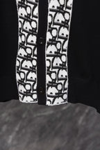 Black cardigan front hem with white patterned trim and two button closures