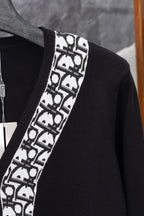 Long black cardigan with white patterned V-edge trim and ribbed neckline