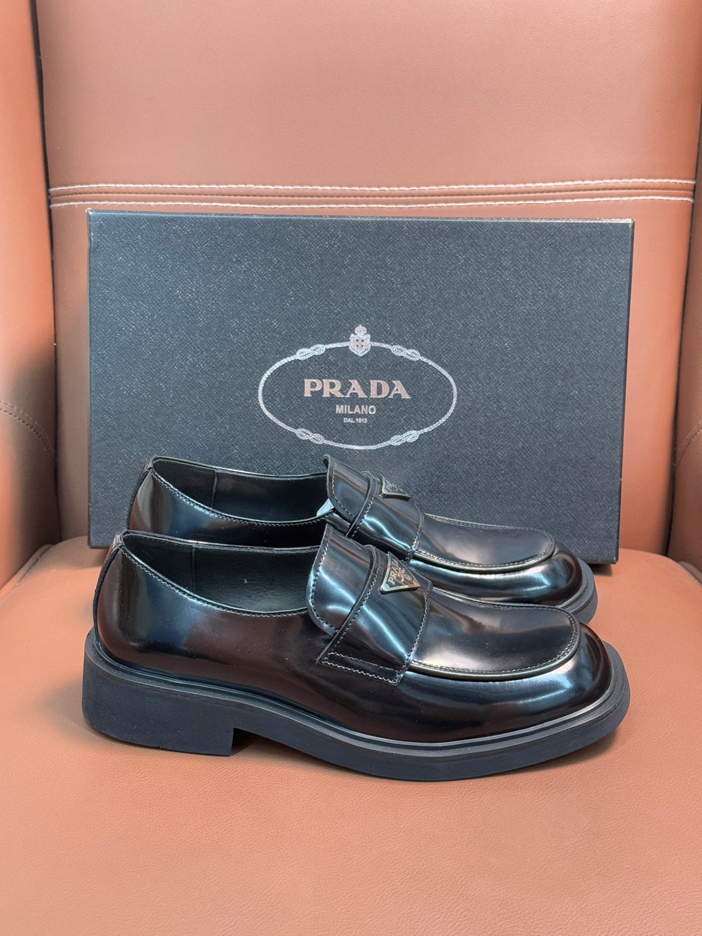 Prada unisex leather loafer with buckle strap, dark glossy upper and thick sole