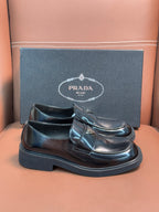 Prada unisex leather loafer with buckle strap, dark glossy upper and thick sole