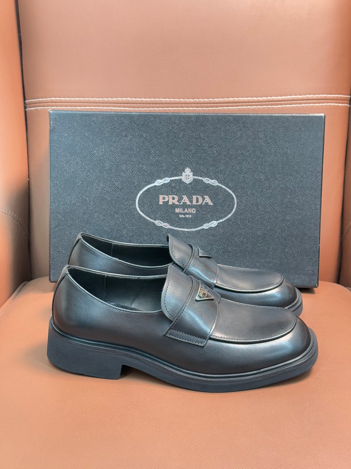 Prada unisex leather loafer with buckle strap, dark glossy upper and platform-like sole