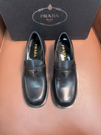 Prada unisex leather loafers, pair front view, dark glossy finish and low stacked soles