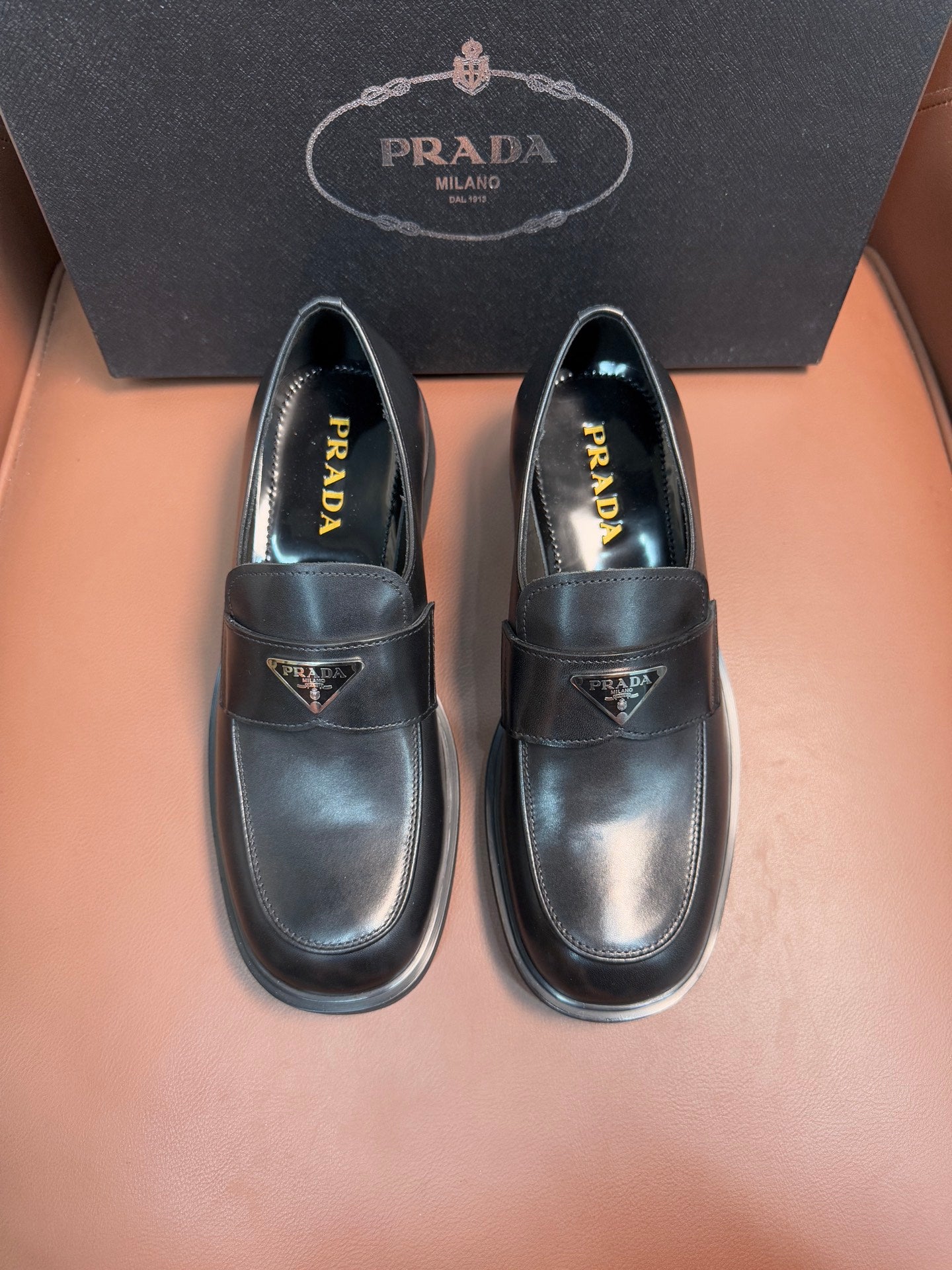 Prada unisex leather loafers, pair front view, dark glossy finish and low stacked soles