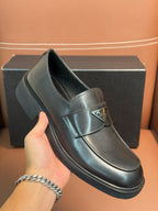 Prada unisex leather loafer close-up, dark glossy finish with buckle detail and sole