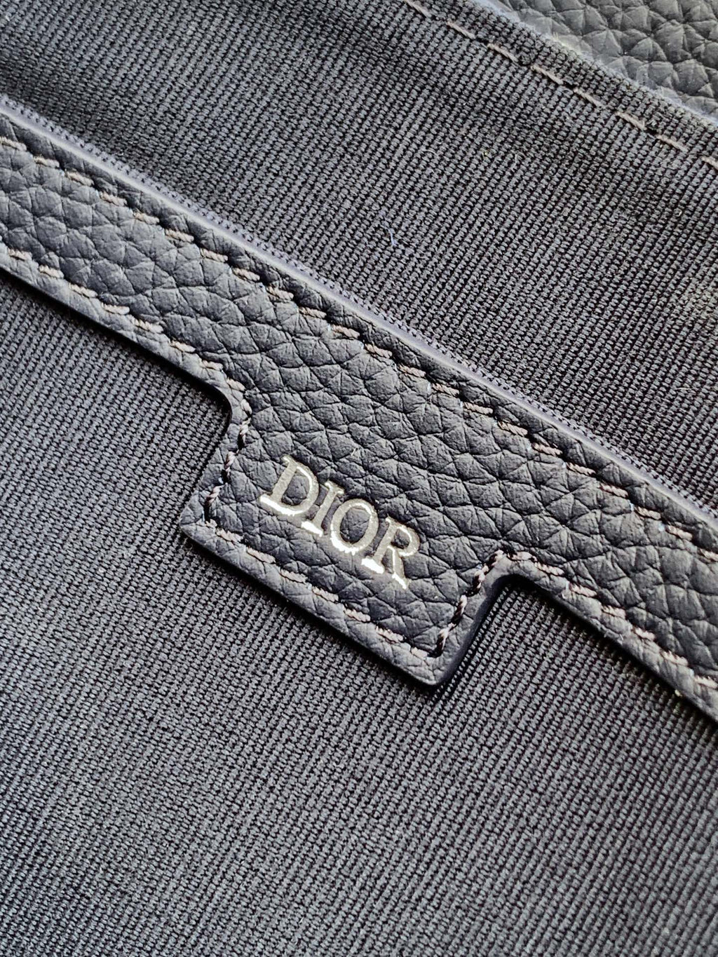 Dior men's bag logo patch on textured gray fabric panel